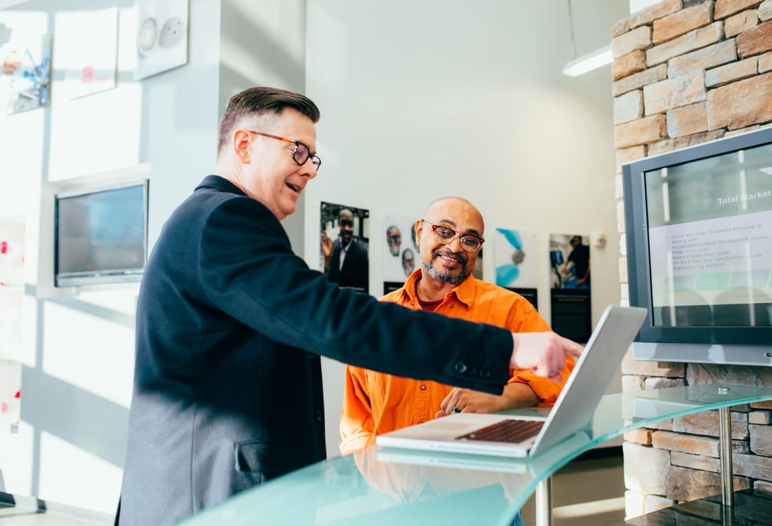 An employer and a junior colleague working together at a laptop